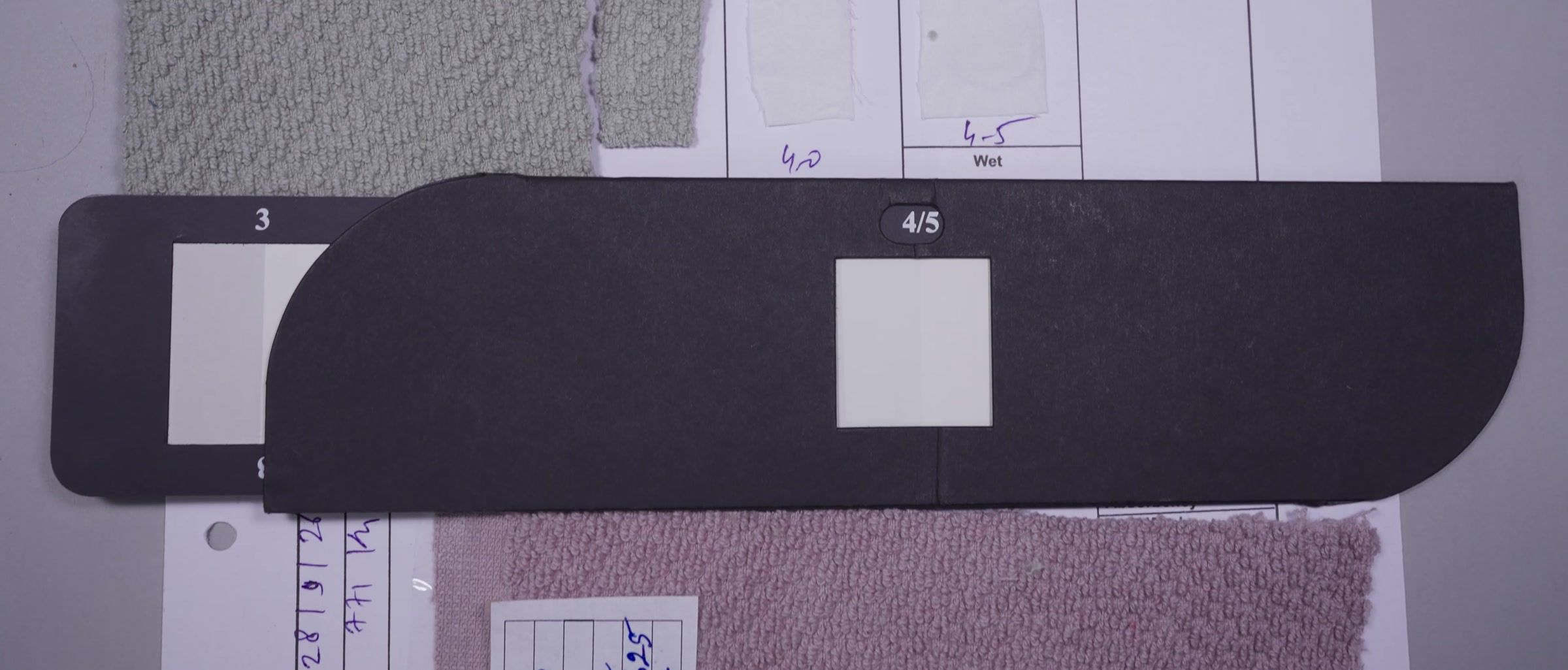 A piece-dyed continuity card: swatches pinned beside a grey scale, with the shade ratings written in.