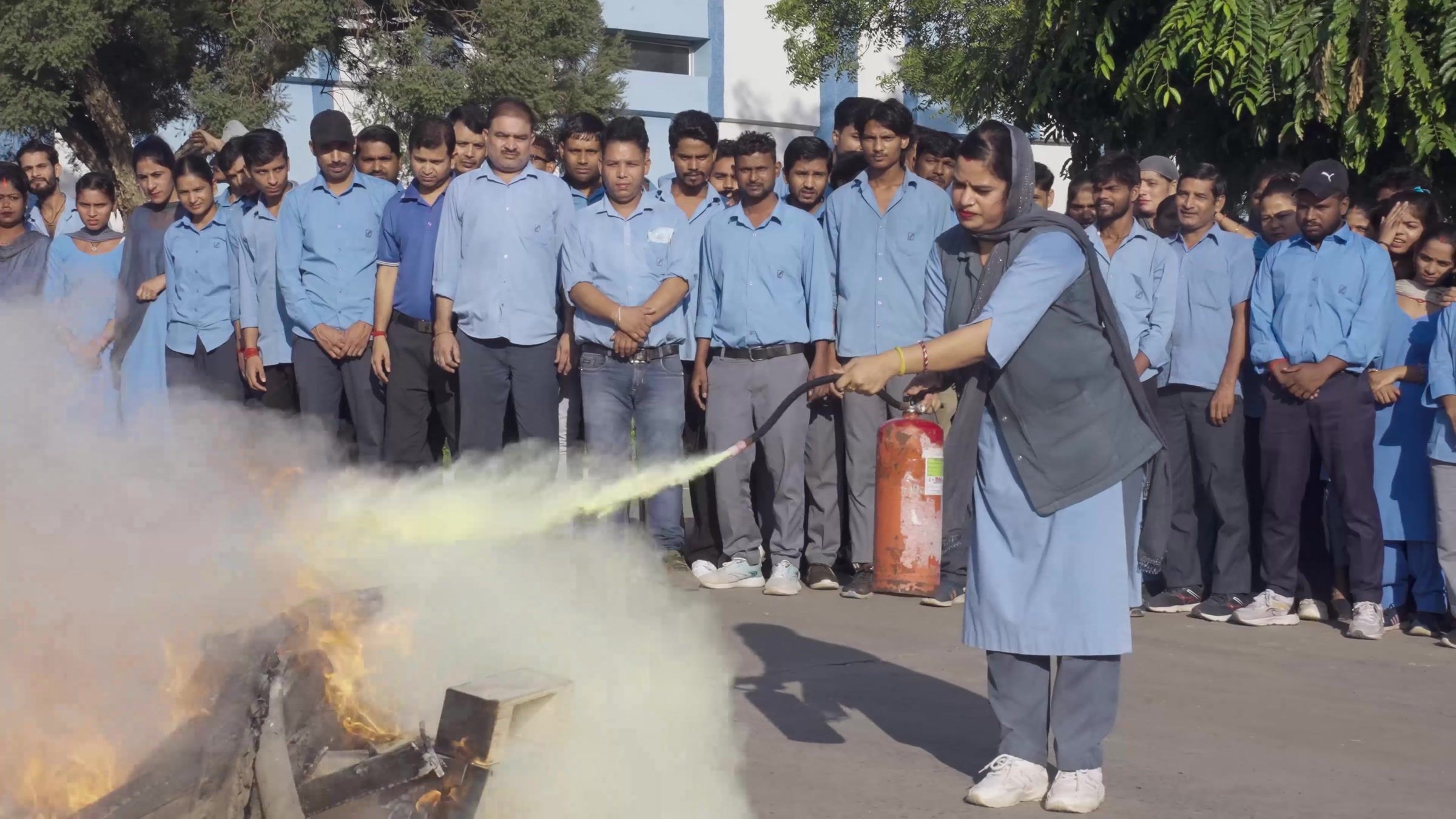 A fire drill on the yard, an extinguisher discharging in front of the assembled shift.