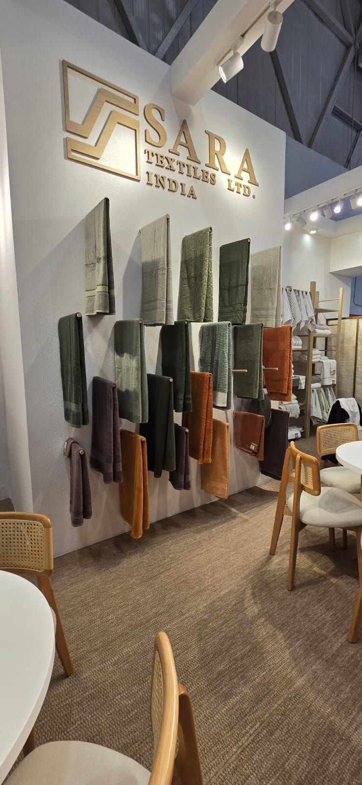 The Sara Textiles sign above a wall of towels graded from olive through rust.