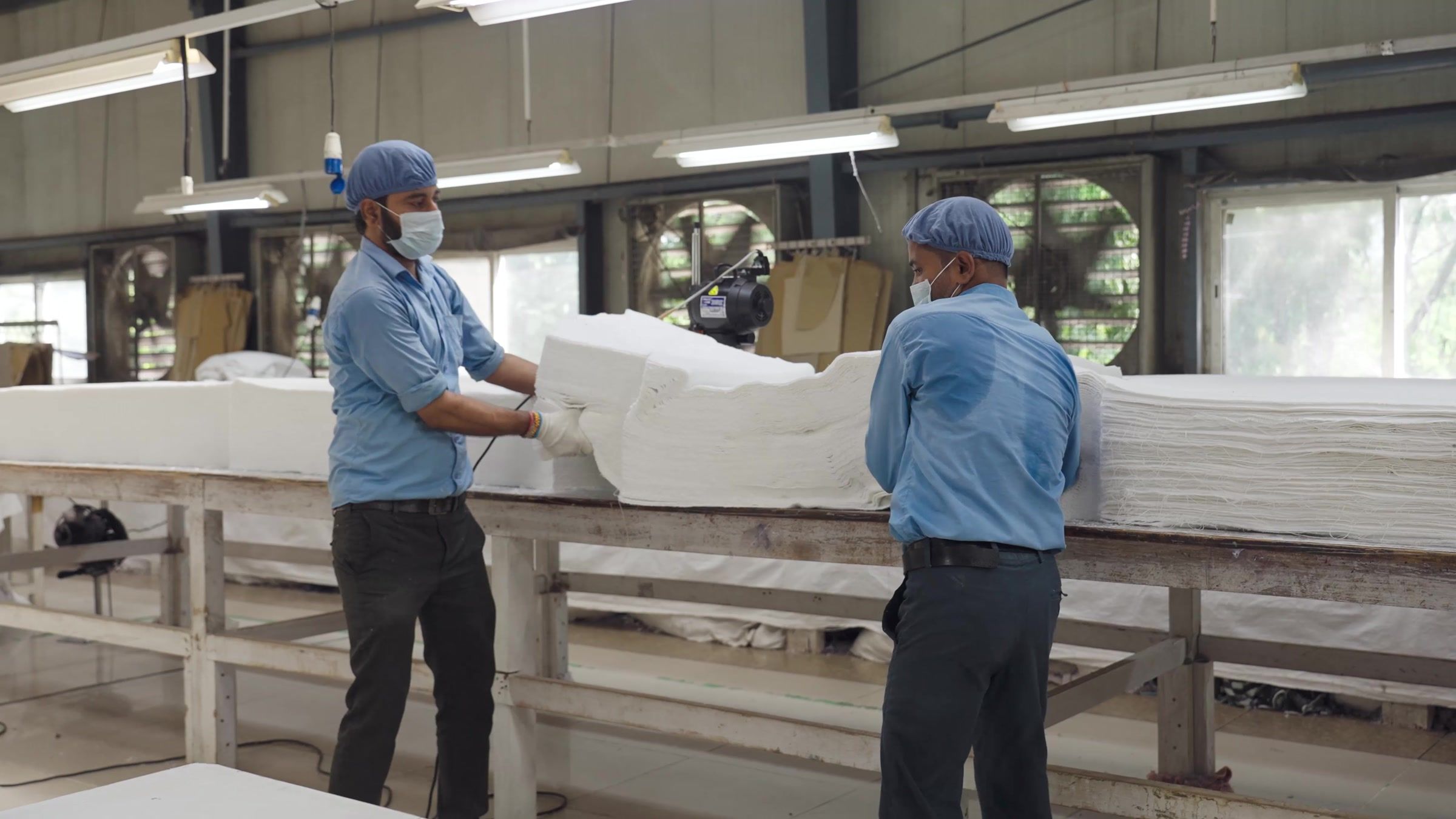 Two of the made-ups team checking folded white goods at the inspection table.