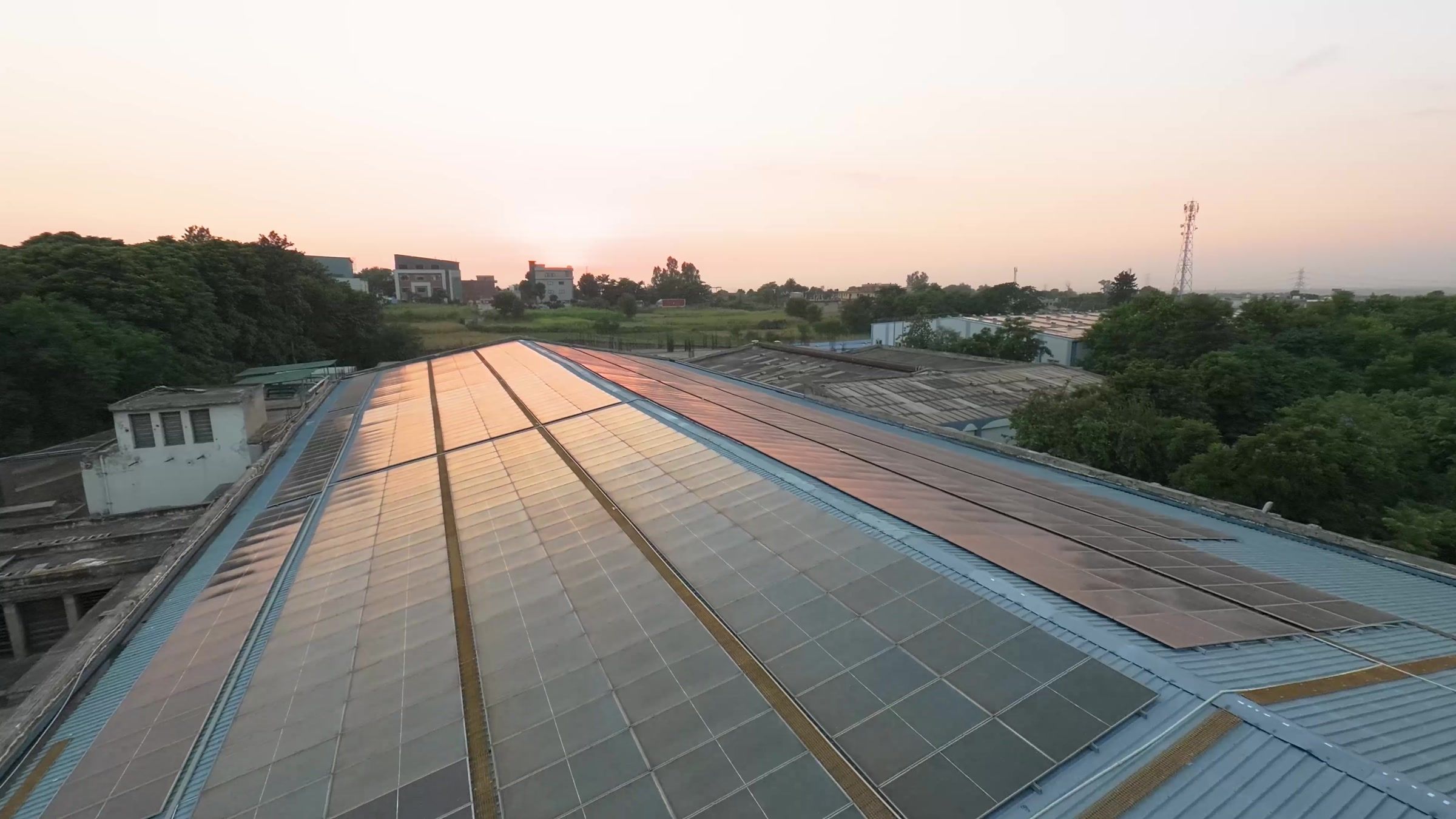 Solar panels running the length of the shed roofs, photographed from the air at dusk.
