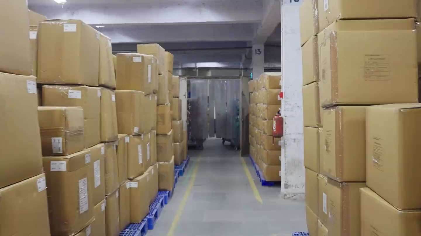 Cartons on pallets in finished goods, and a container being loaded in the yard.