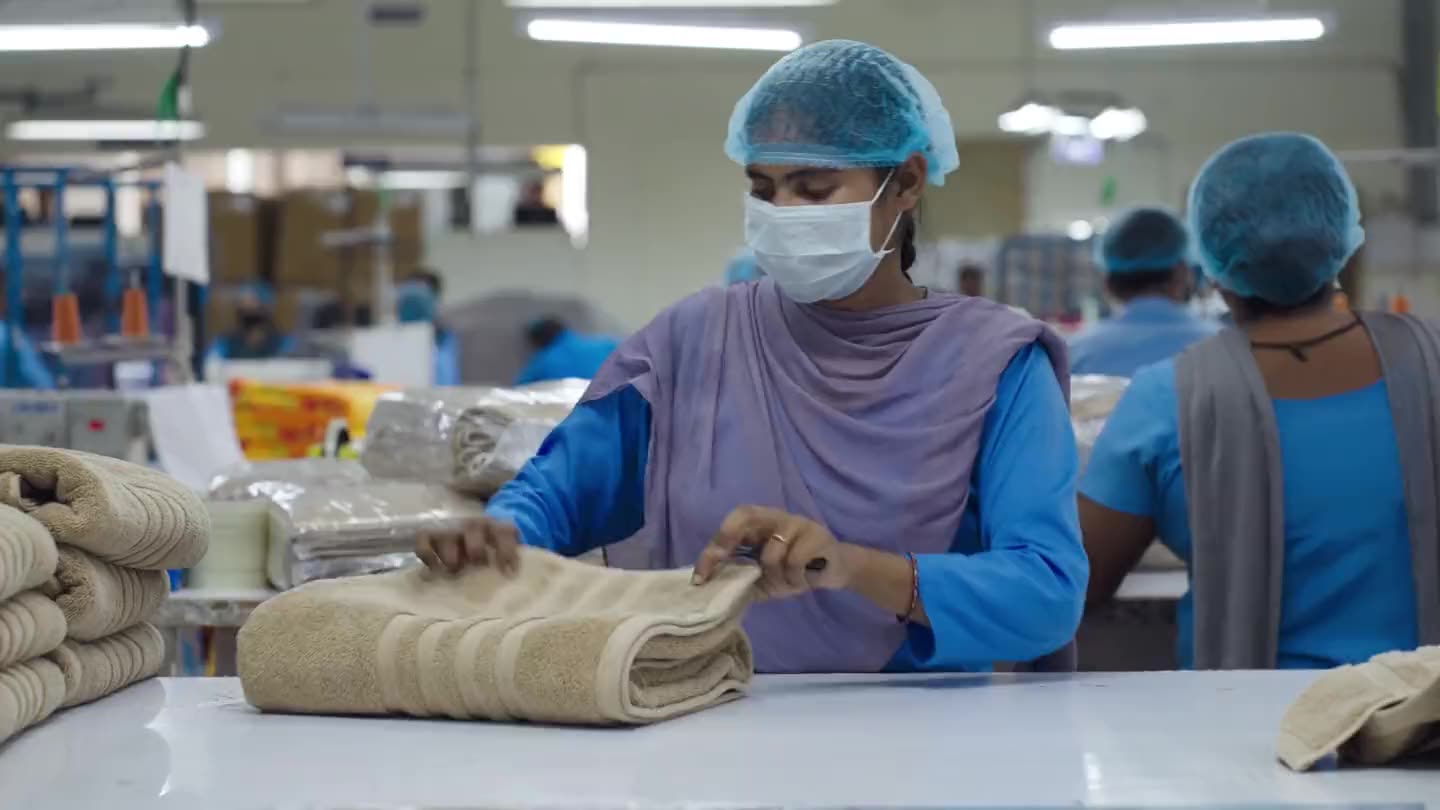 An operator folding a finished towel at the inspection table on the made-ups floor.
