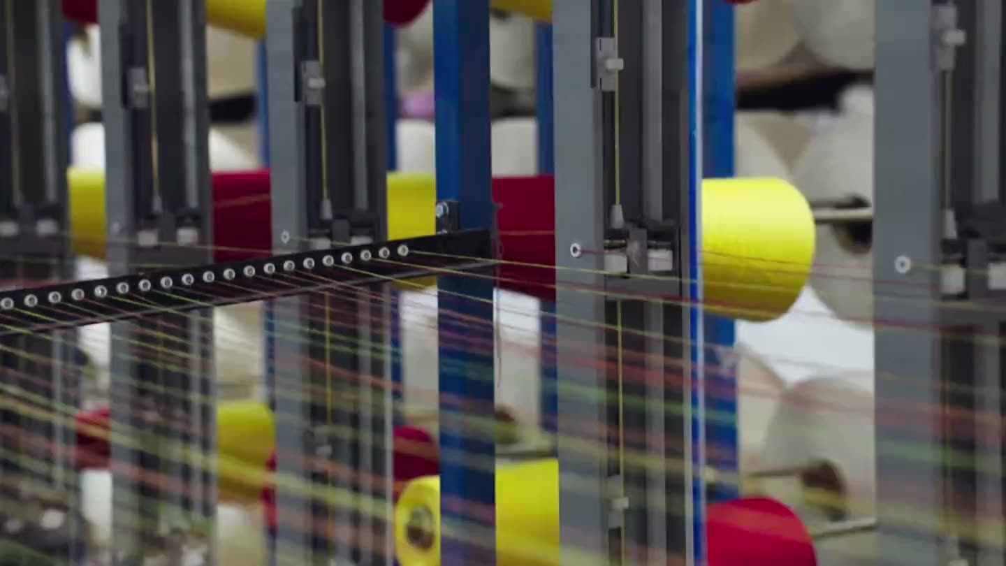 Coloured warp yarns running through the creel guides on their way to the beam.